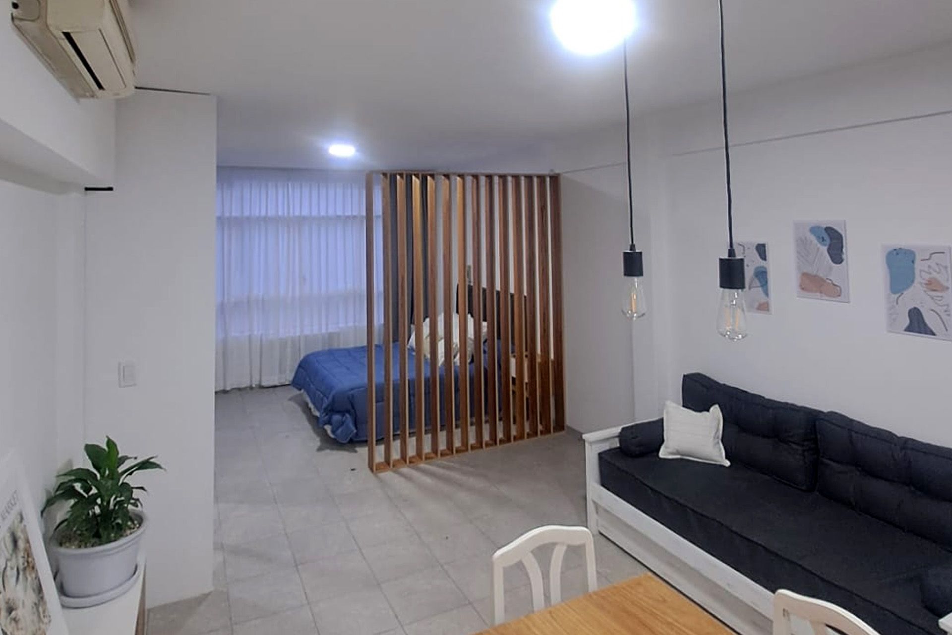 Un salón de tonos neutros con un televisor montado en la pared, dos estanterías de madera, dos mesas pequeñas y sofás de color crema.