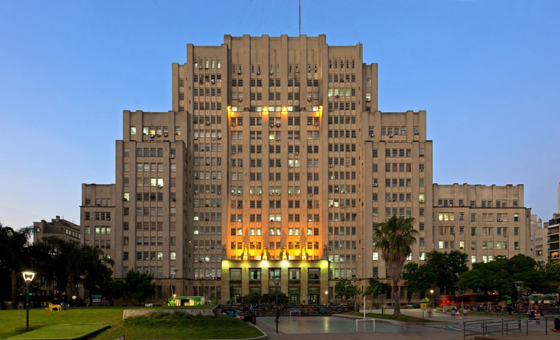 Un puente blanco sobre un lago con un barco. Está rodeado de árboles y césped verde.