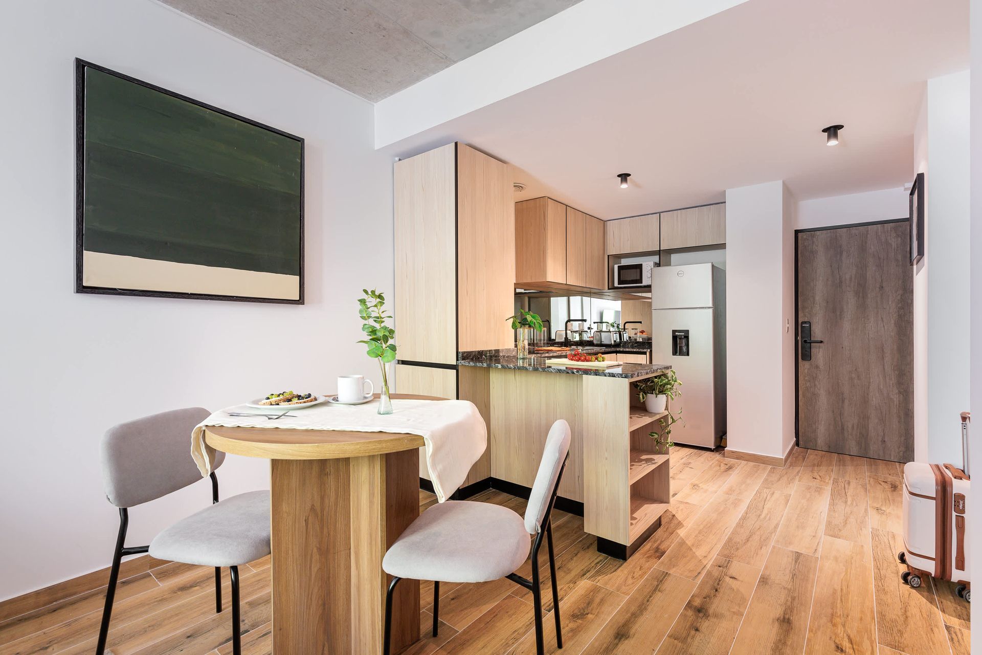 Camino a través de un jardín de rosas con gente sentada en bancos. Rosas rosas y rojas, árboles y un cielo azul.