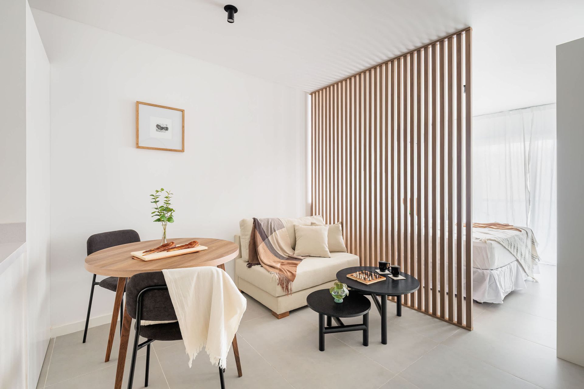Sala de estar con detalles de madera, mesa de comedor, sofá blanco y obras de arte en la pared.