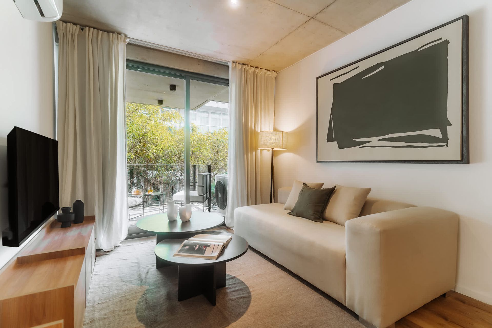 Un moderno estudio tipo apartamento que cuenta con un juego de comedor de madera, una cocina compacta con gabinetes de madera clara y pisos de madera noble.