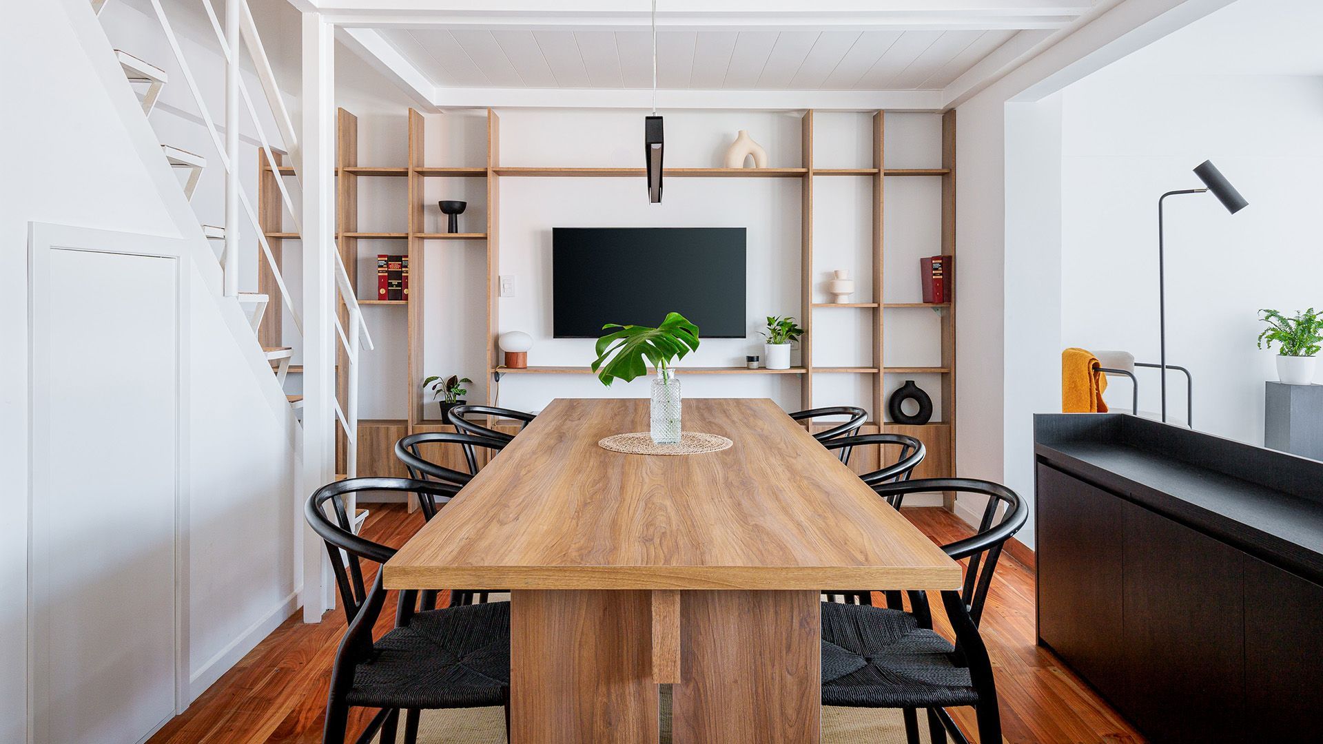 Camino a través de un jardín de rosas con gente sentada en bancos. Rosas rosas y rojas, árboles y un cielo azul.