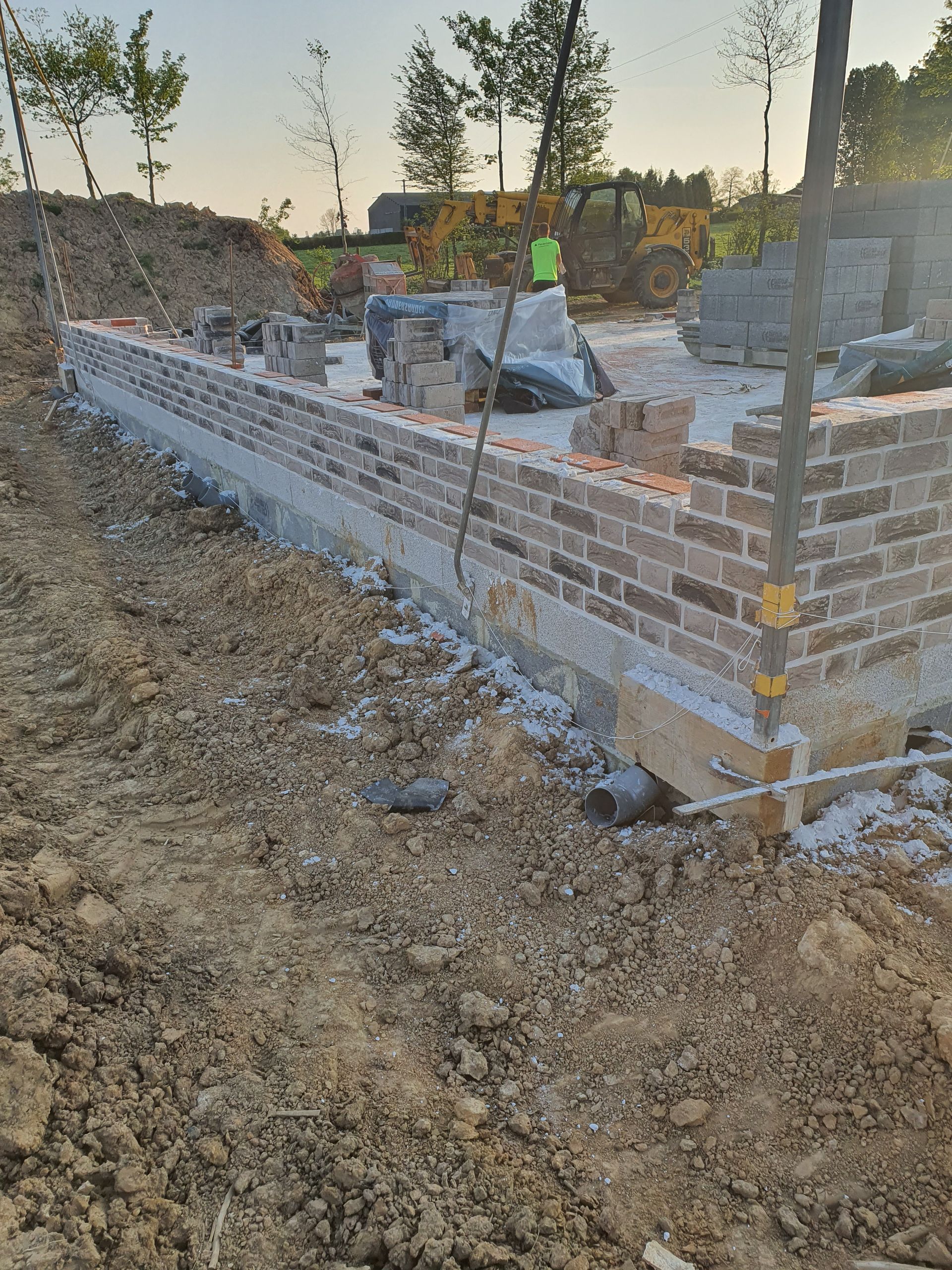 Le mur de fondations est construit avec des briques brunes et du béton.