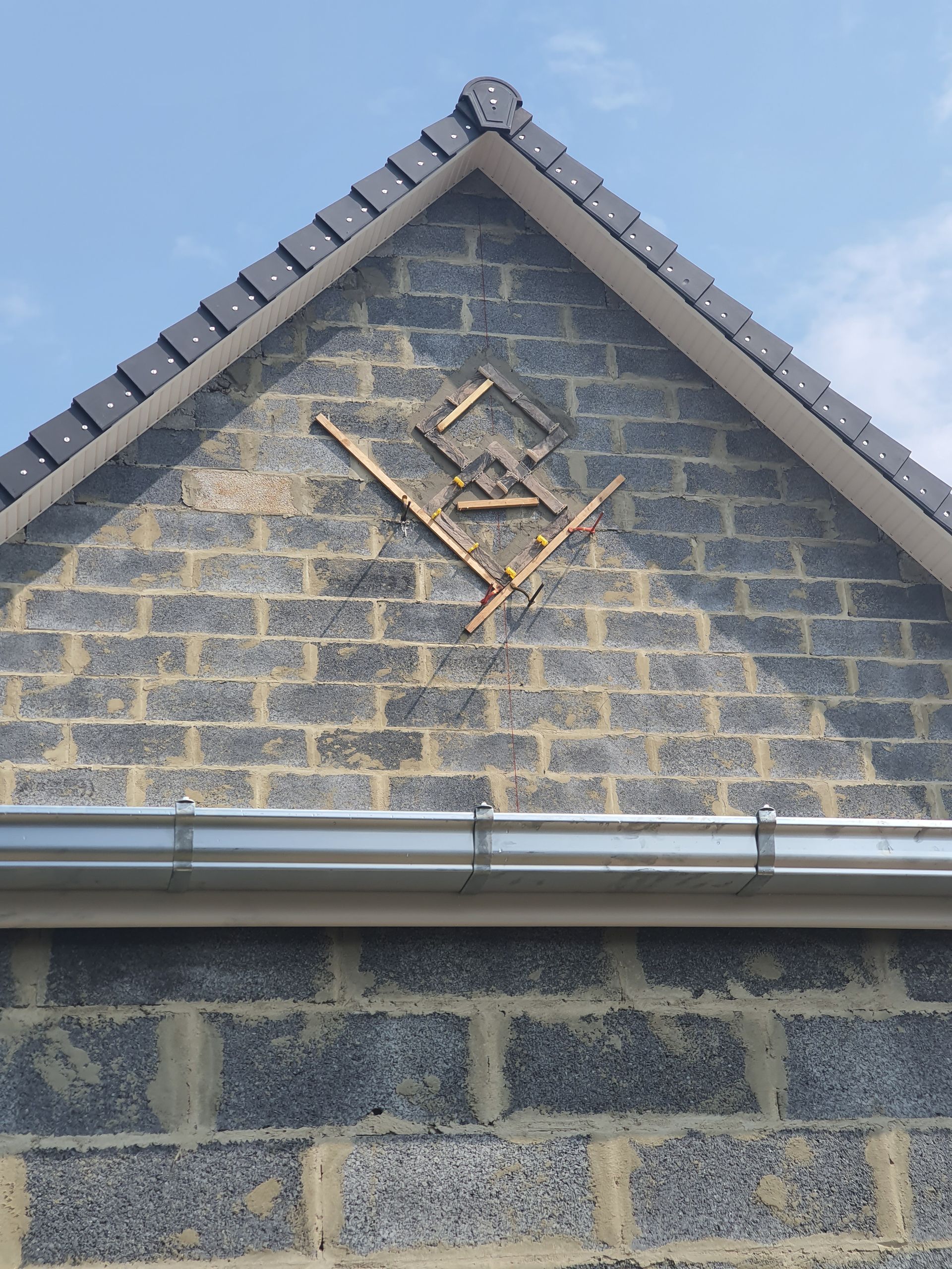 Symbole sur un mur de briques sous un toit foncé.