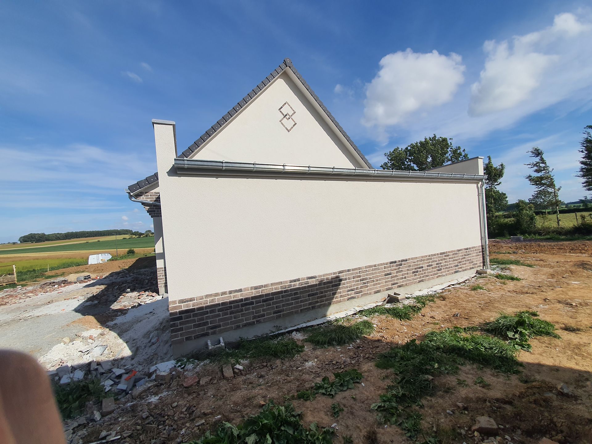 Vue latérale d'une maison en construction, avec des murs clairs.