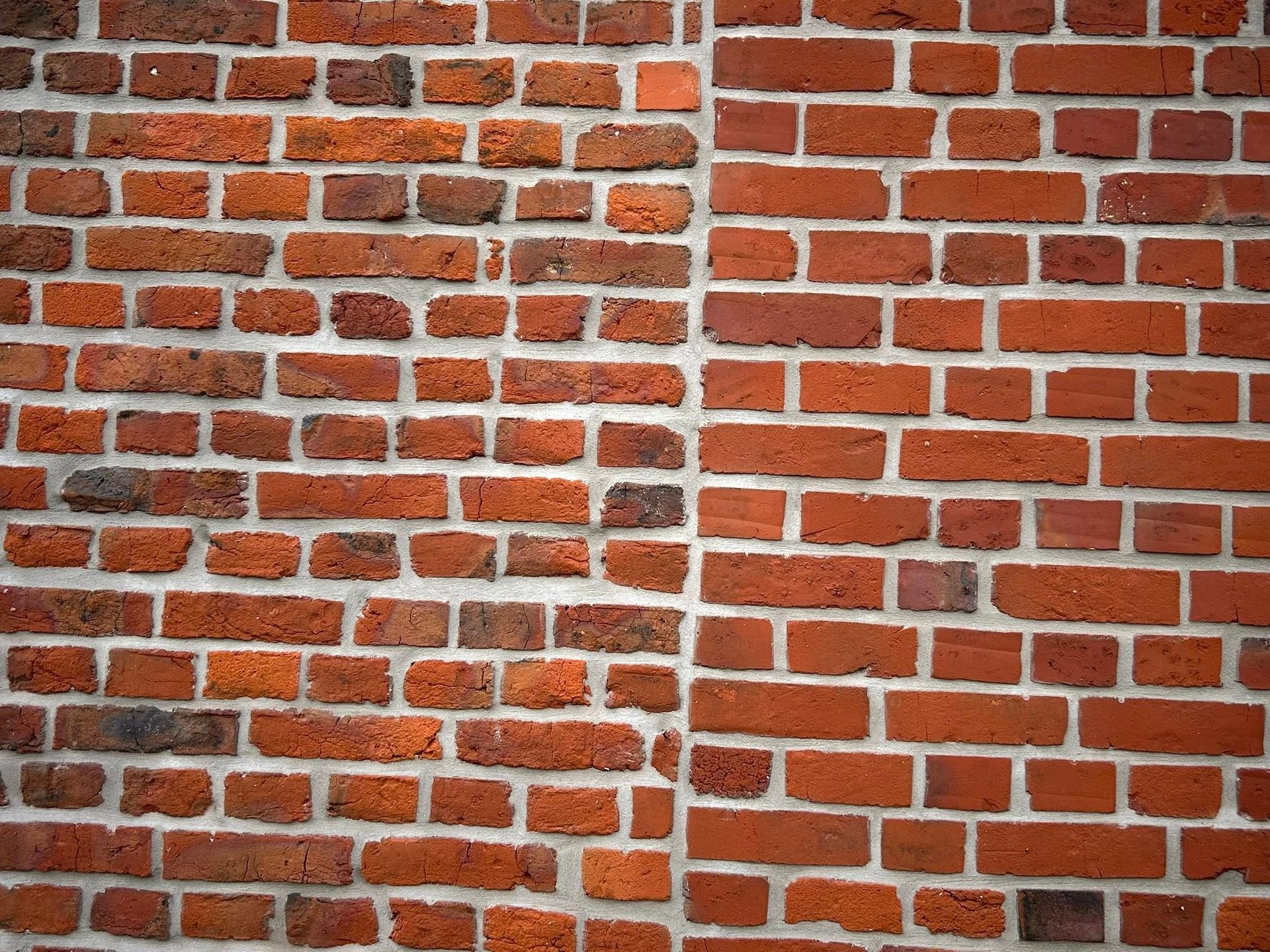Mur en briques rouges présentant deux motifs de construction distincts.