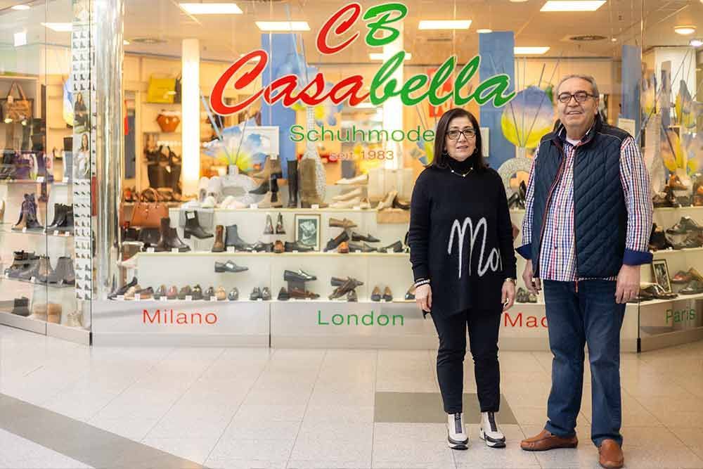 Zwei Personen stehen vor einem Schuhgeschäft namens Casabella, in dessen Schaufenstern Schuhe ausgestellt sind.