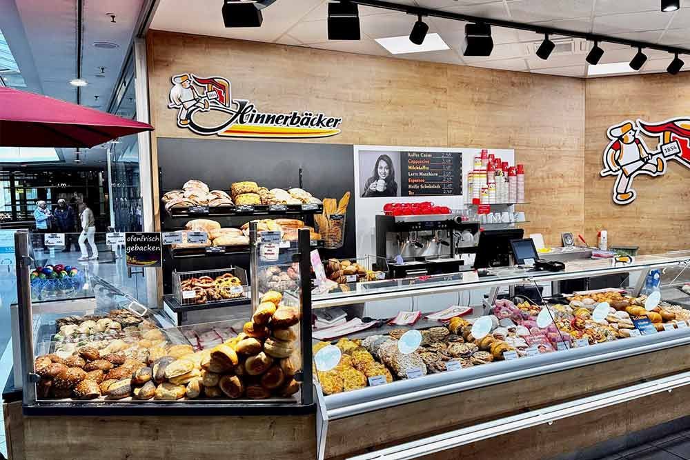 Auslage einer Bäckerei mit verschiedenen Backwaren und Kaffeemaschine.