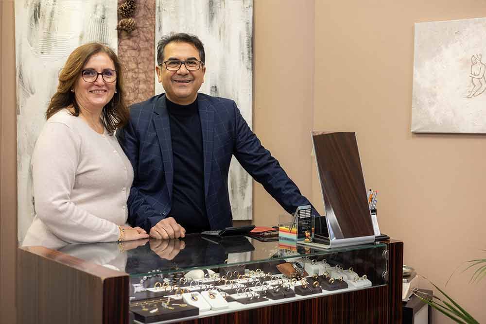 Zwei Personen, ein Mann und eine Frau, lächeln hinter einem Schmuckauslagetisch in einem Geschäft.