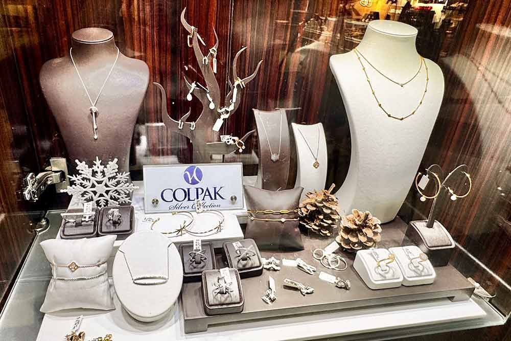 Schmuckvitrine mit Halsketten, Armbändern und Ohrringen auf Schaufensterpuppen und Tabletts.