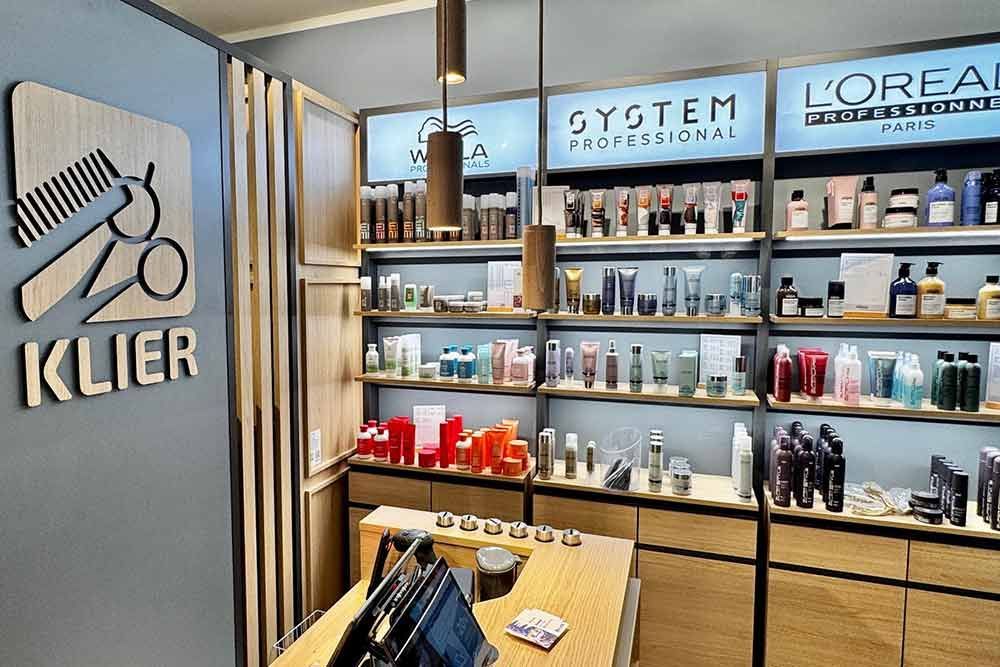 Inneneinrichtung eines Friseursalons mit Produktpräsentationsregalen und dem Logo „Klier“.