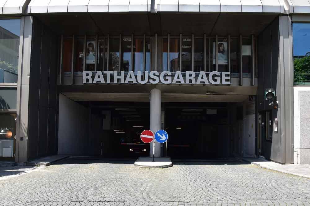 Einfahrt zum Parkhaus „Rathausgarage“ mit Beschilderung. Kopfsteinpflaster. Blaue und rote Verkehrsschilder.