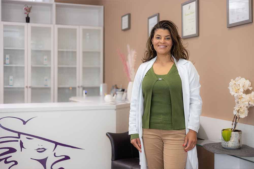 Eine Frau im weißen Kittel steht in einem hell erleuchteten Arztzimmer.