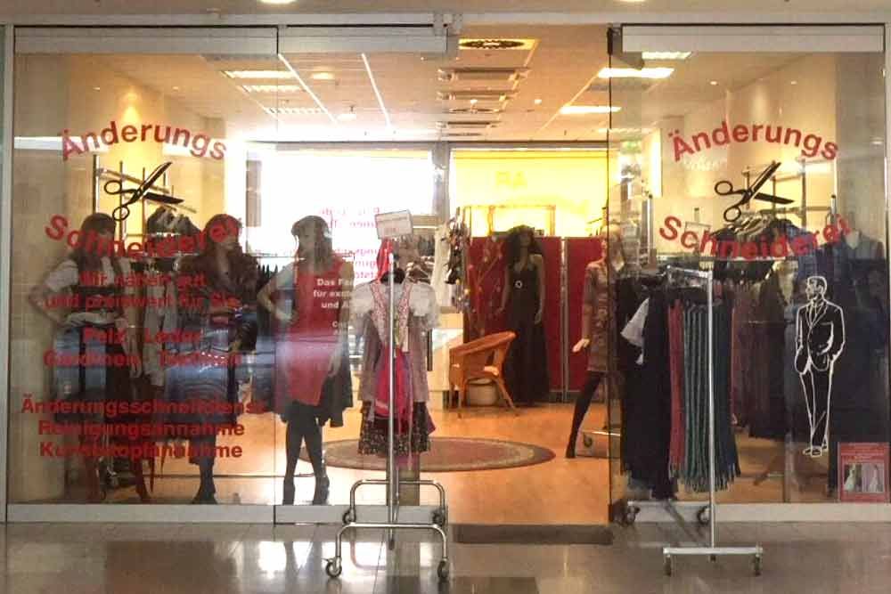 Schaufenster einer Änderungsschneiderei mit Schaufensterpuppen und ausgestellter Kleidung.