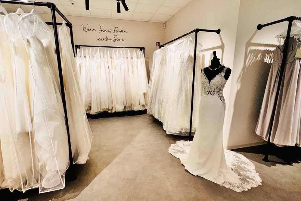 In einem Brautmodengeschäft werden Brautkleider ausgestellt; eine Schaufensterpuppe in der Mitte präsentiert ein Kleid mit langer Schleppe.