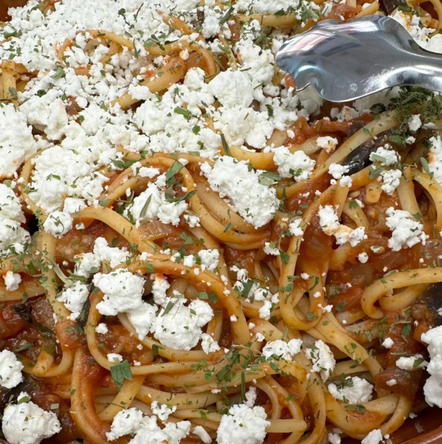 Un primer plano de un plato de pasta con una cuchara dentro.