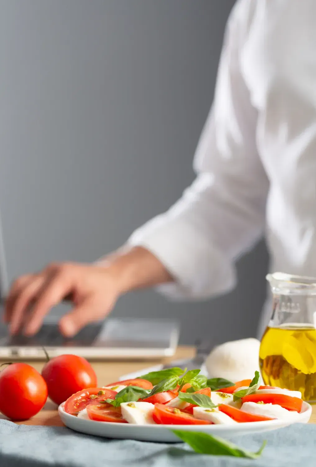Una persona está escribiendo en una computadora portátil al lado de un plato de comida.