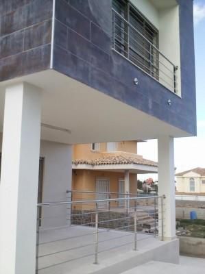 Un balcón en el lateral de un edificio con barandilla de acero inoxidable.