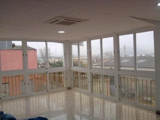 Una habitación grande con muchas ventanas y balcón.