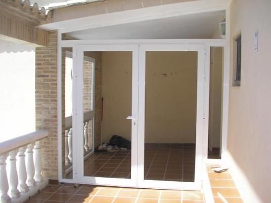 Un balcón con una puerta blanca y una pared de ladrillo.