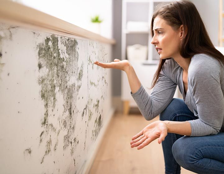 Femme choquée devant un mur moisi