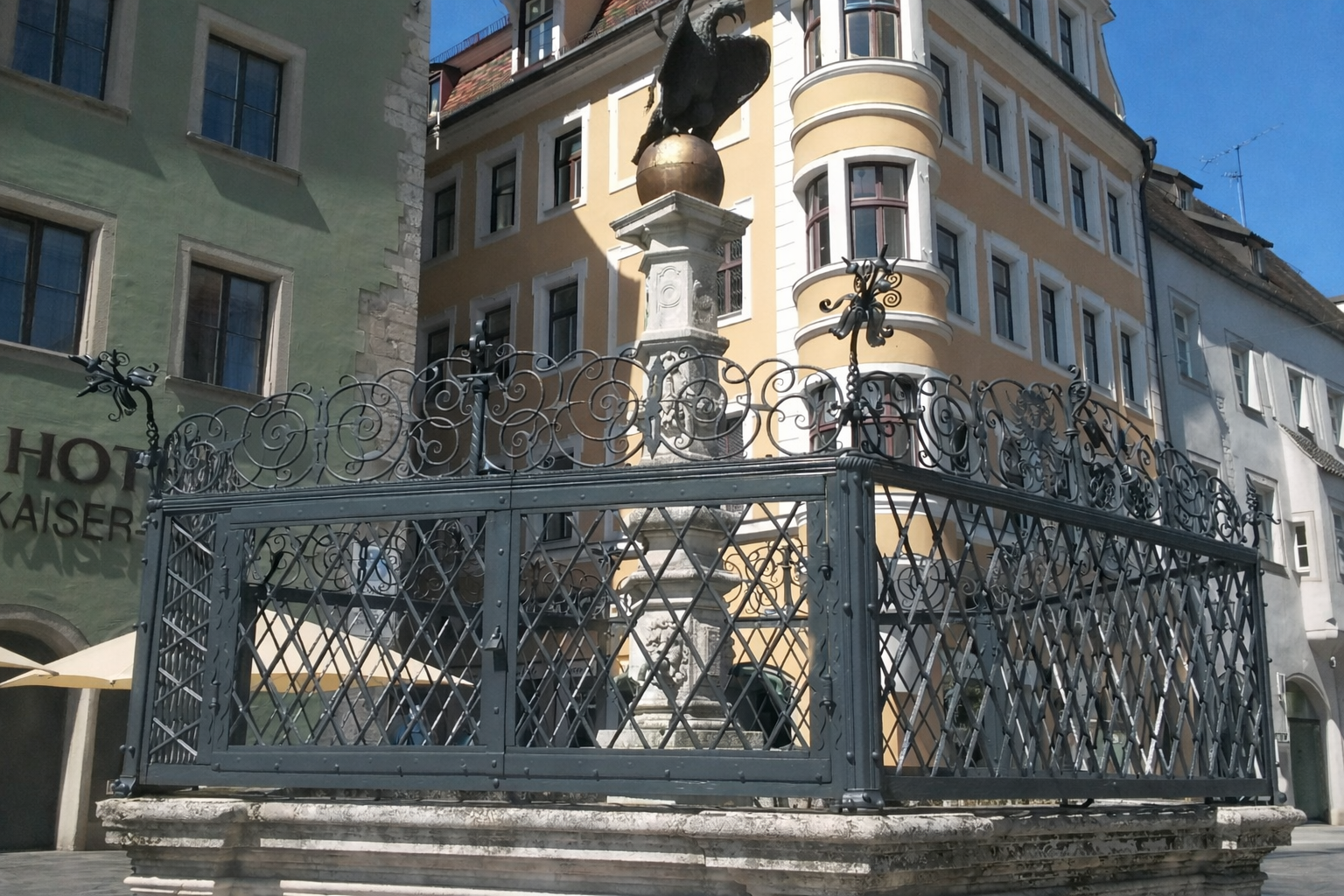 Geschwungene Treppe mit dekorativem, schwarzem Schmiedeeisengeländer, die durch ein Glasbausteinfenster beleuchtet wird.