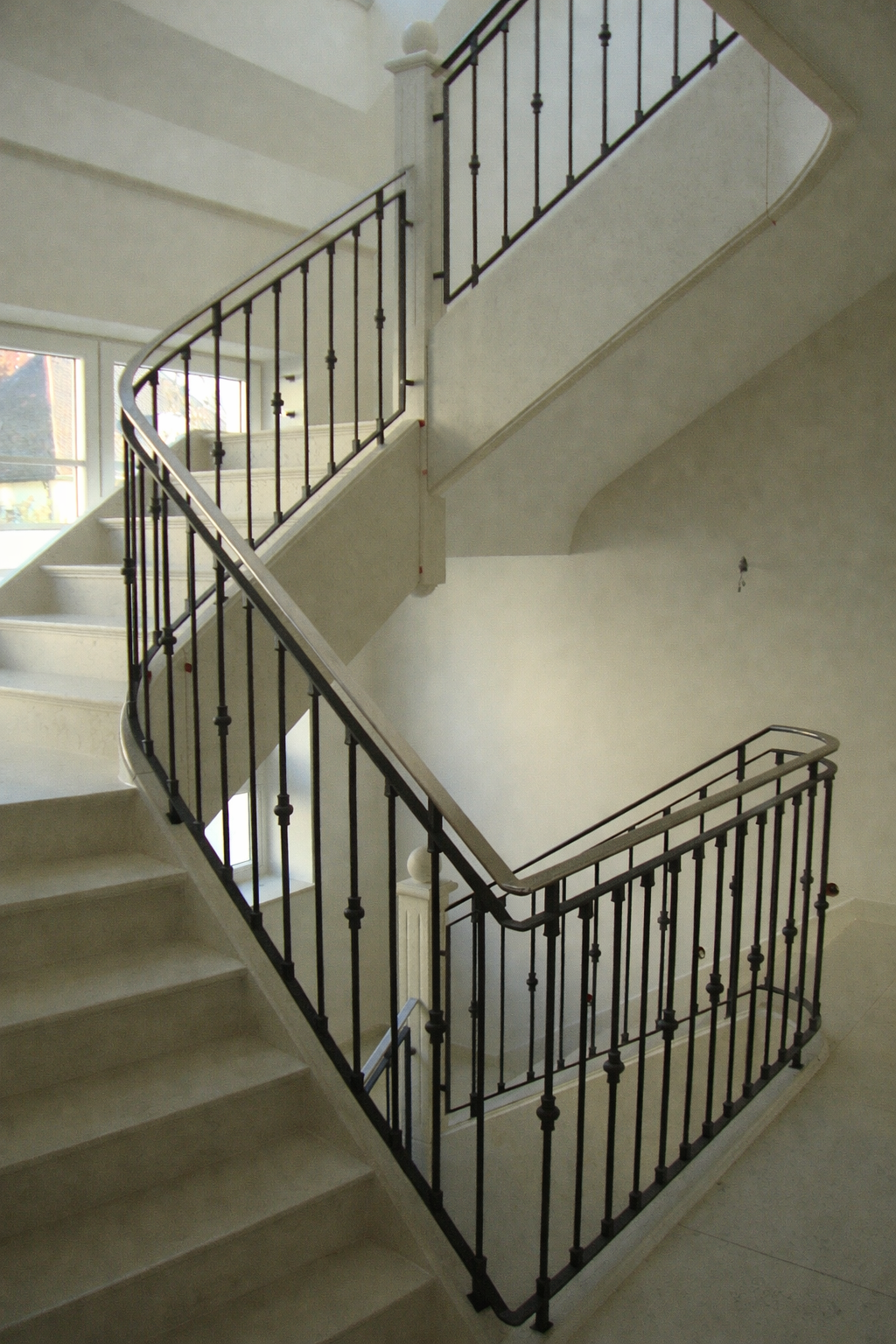 Dunkelgraues Metalltor mit Hausnummer 6 an einer weißen Wand.