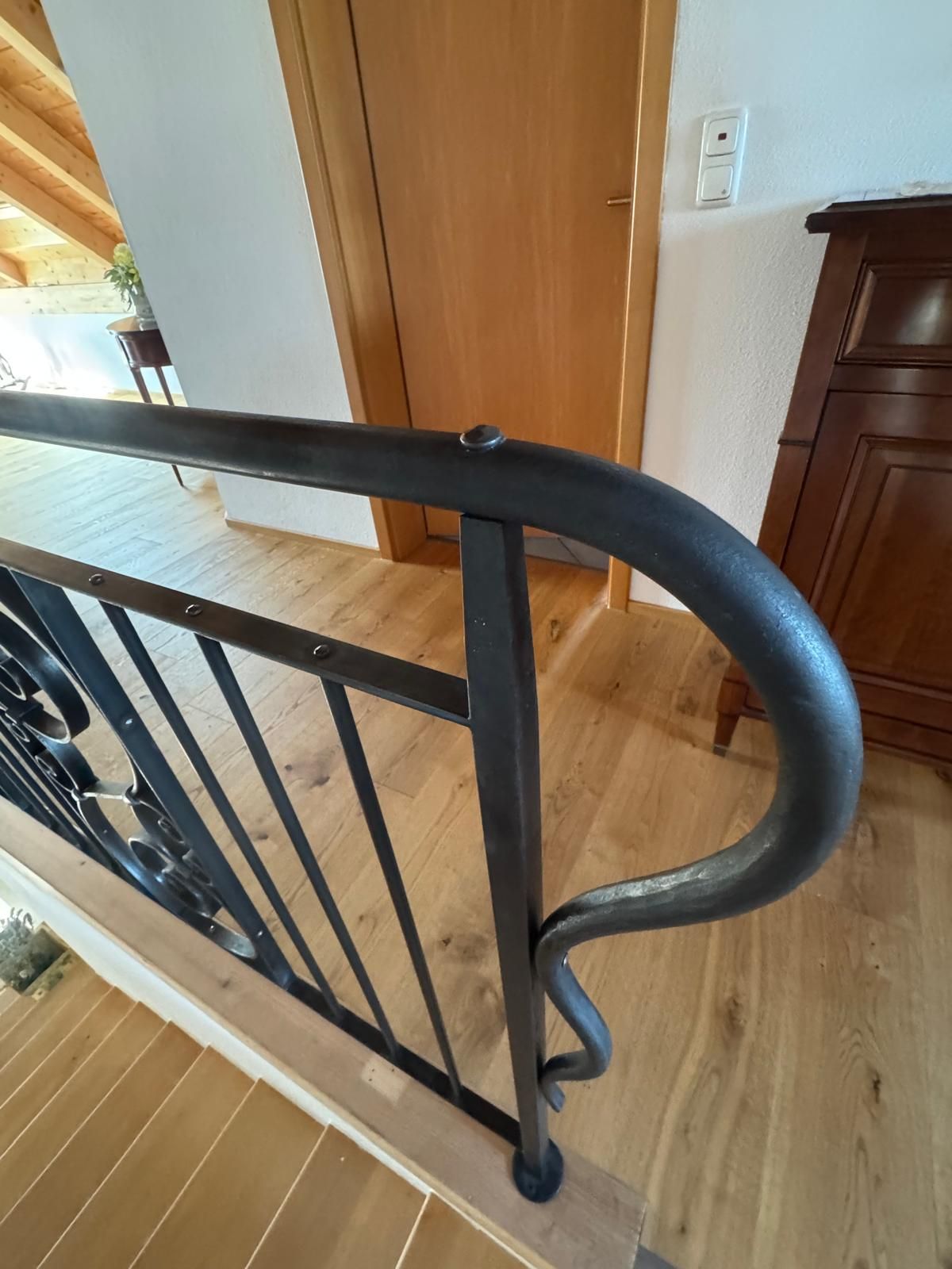 Verzierte, schwarze schmiedeeiserne Tore. Eingang zu einem Gebäude mit Steinmauern und sichtbarem Innenhof.