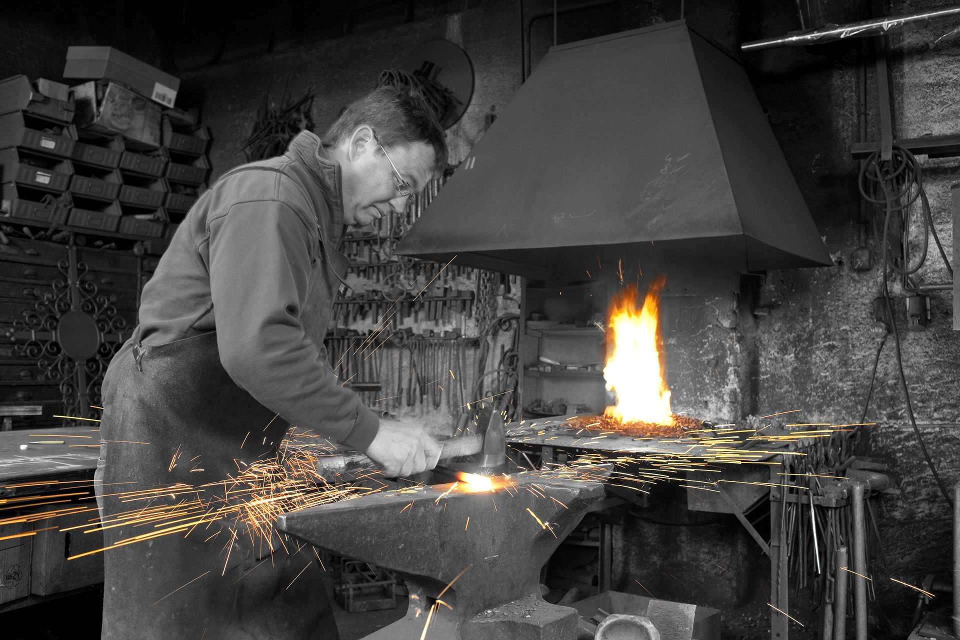 Schwarzer Holzaltar mit einer Kerze und zwei Votivgaben auf hellem Boden, vor einer Wand mit einem Kruzifix.