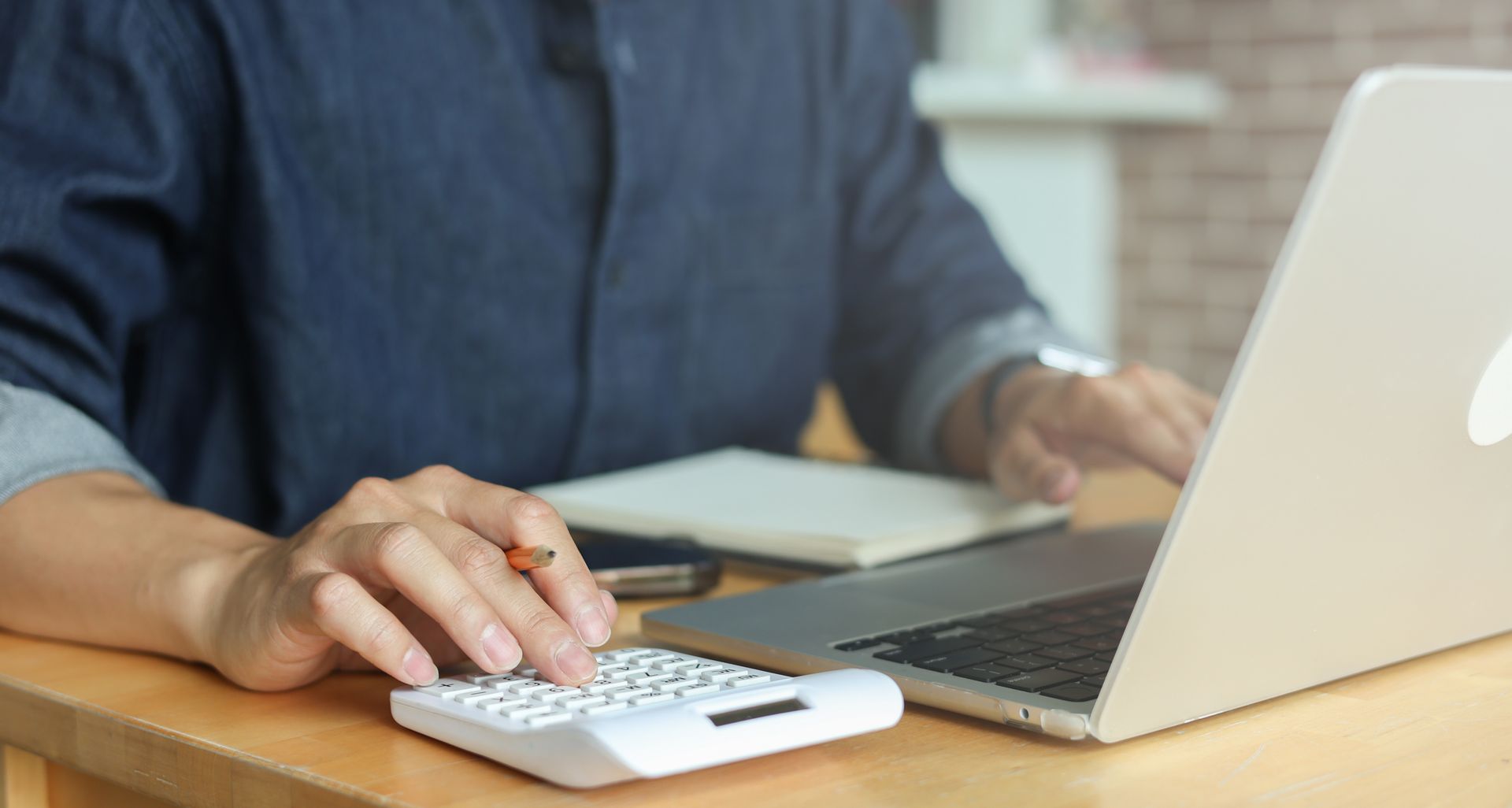 Une personne utilise une calculatrice et un ordinateur portable.