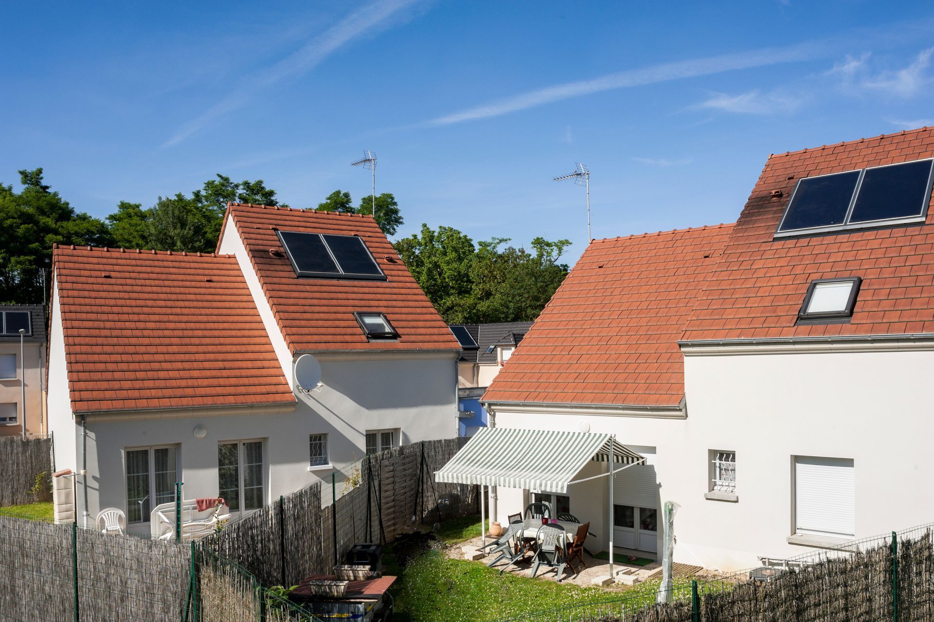 Deux maisons blanches aux toits de tuiles rouges, des panneaux solaires.