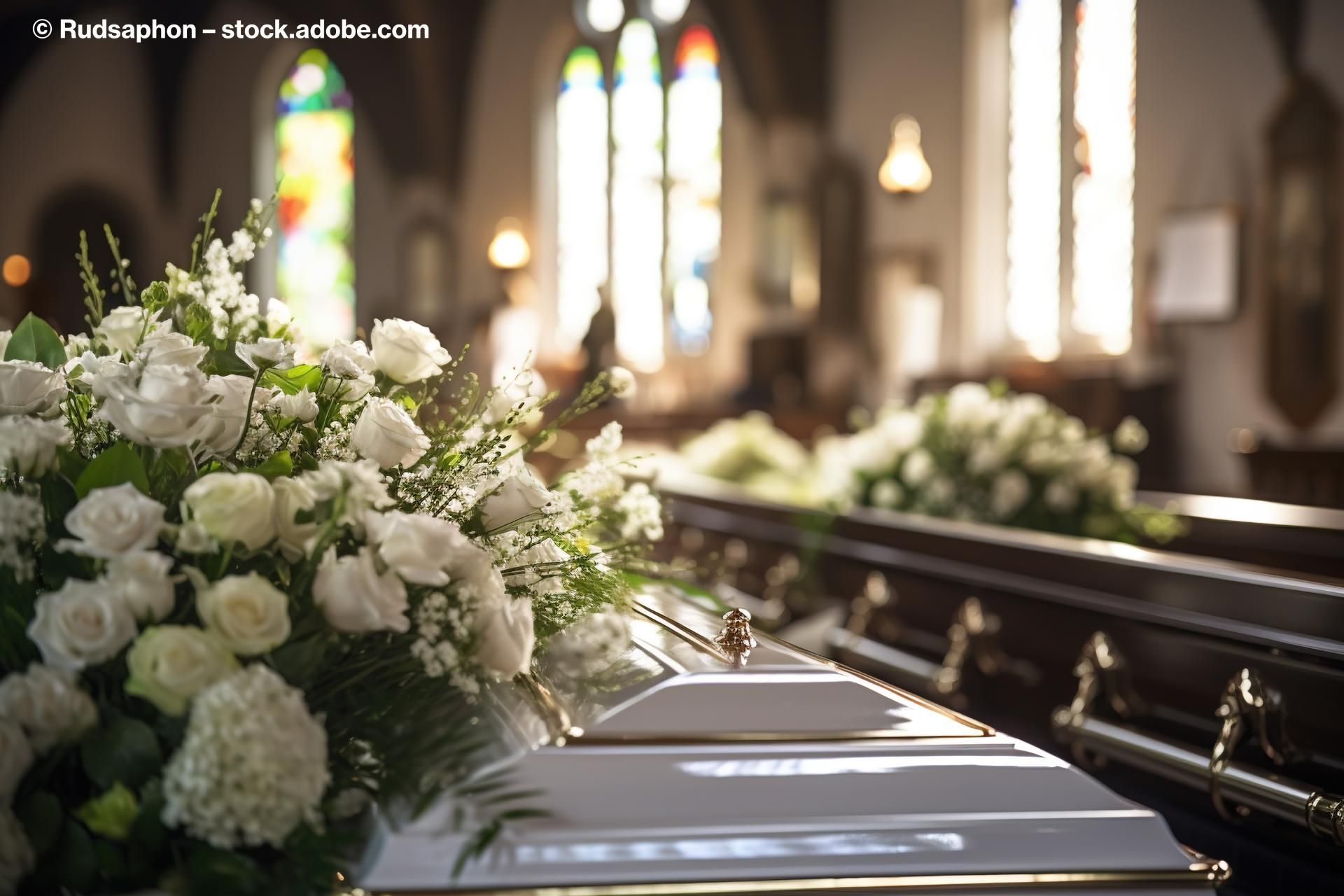 Ein weißer Sarg mit einem weißen Blumenstrauß in einer Kirche