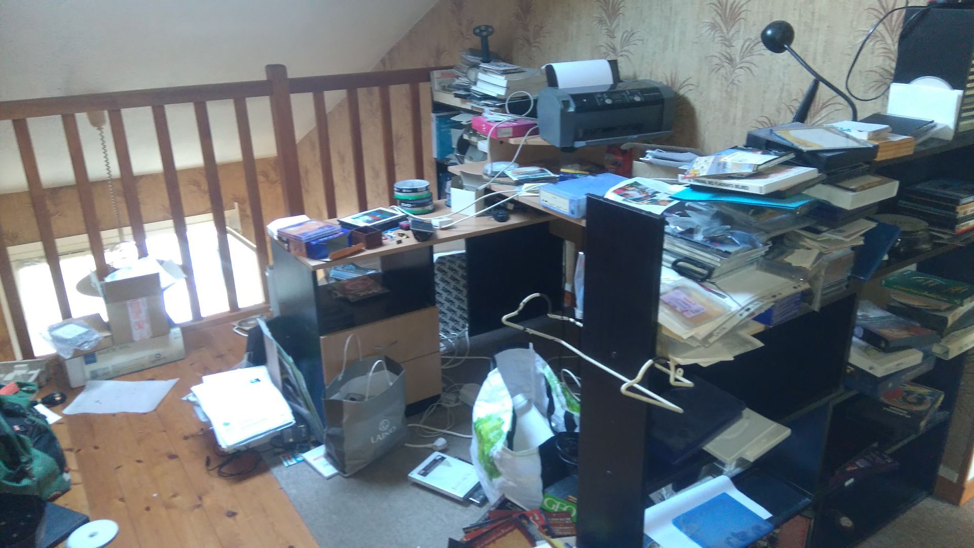 Mezzanine en désordre avec bureau, étagères, imprimante encombrés et rambarde en bois