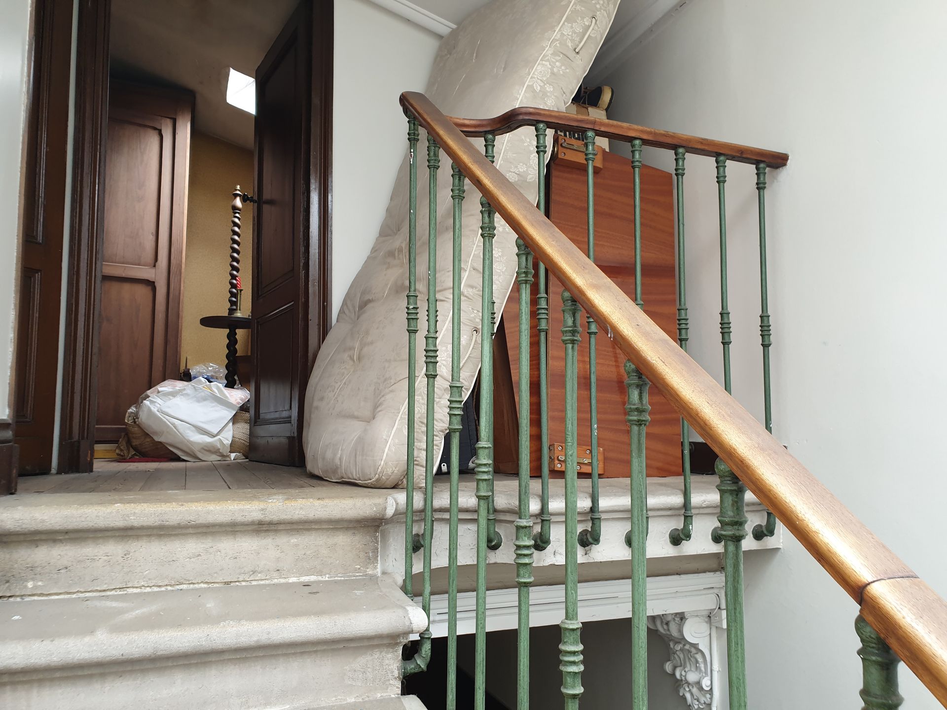Matelas et meubles sur un escalier, obstruant les marches et la porte