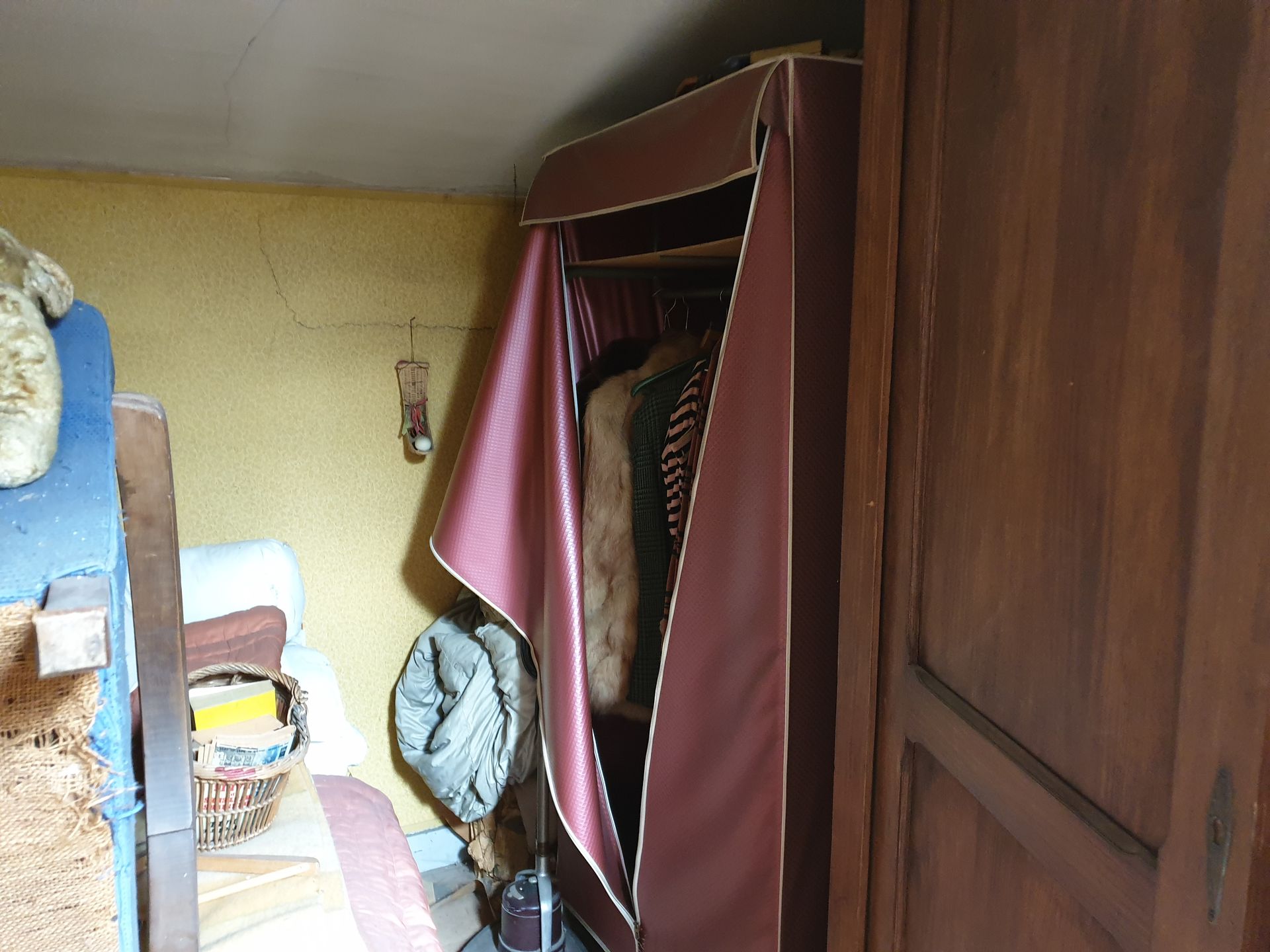 Placard recouvert d'un tissu bordeaux, laissant apparaître des vêtements suspendus