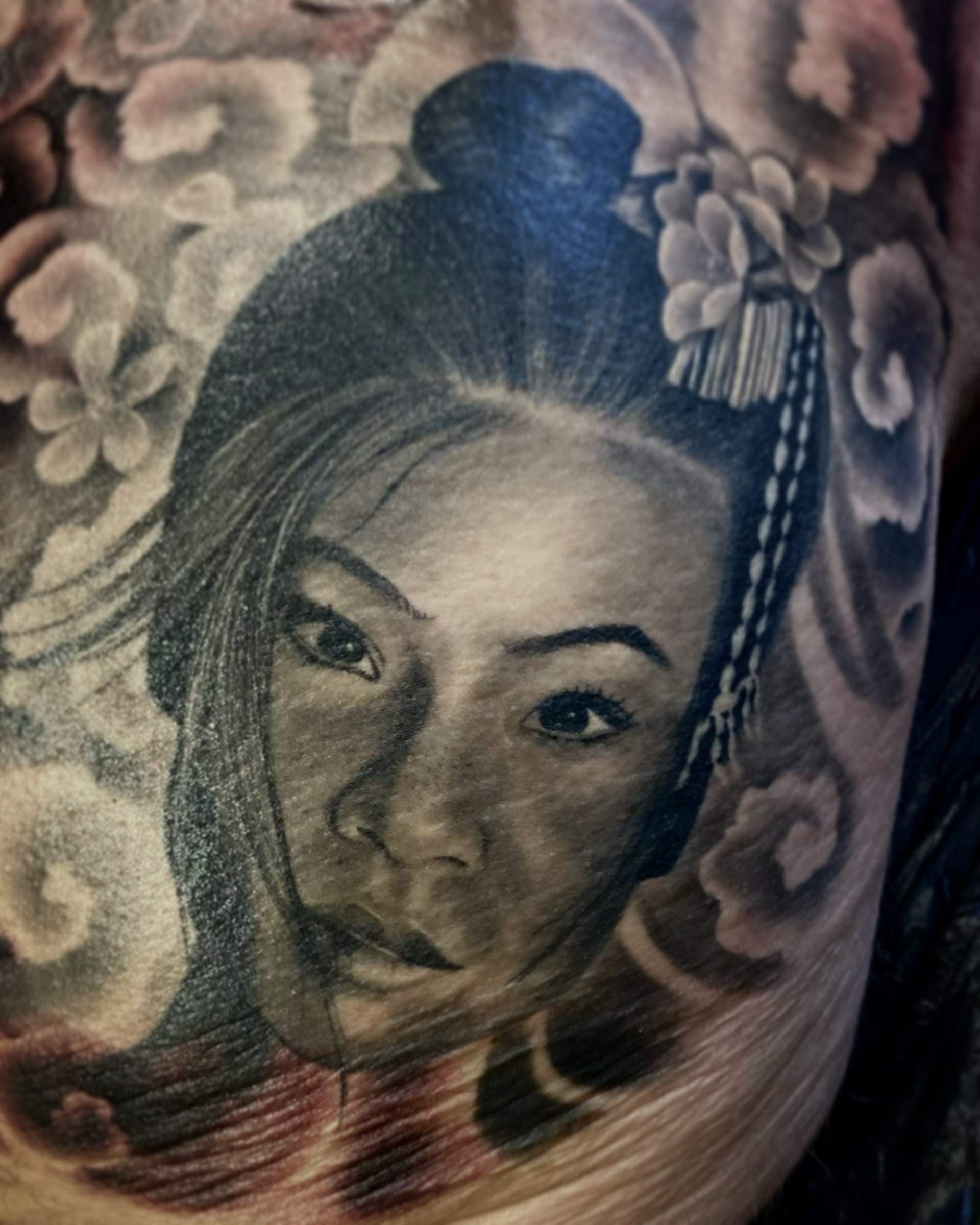 Ein asiatisch angehauchtes Black and White Tattoo, eine asiatische Frau mit Blumen im Hintergrund