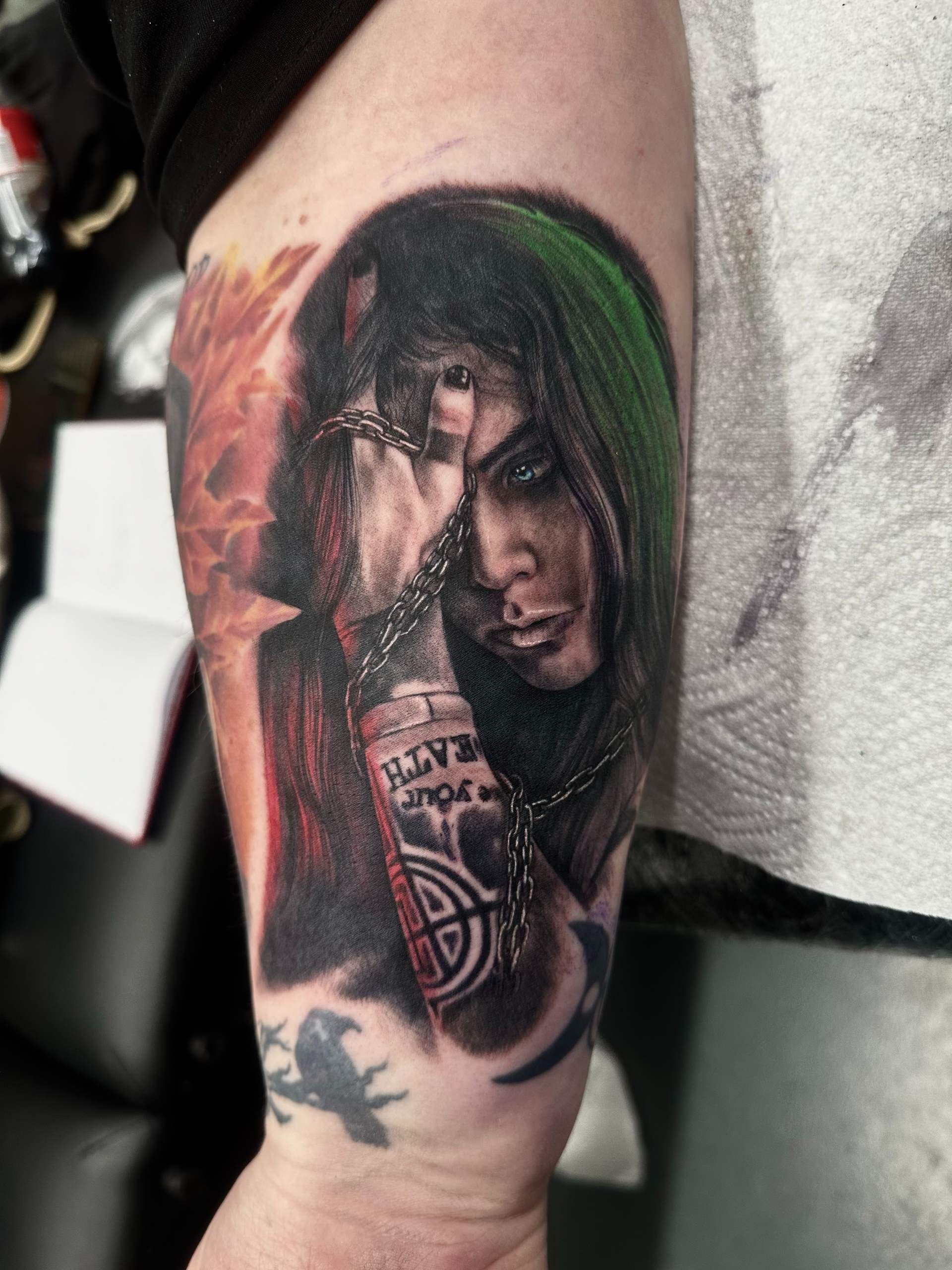 Tattoo mit Farbe, Frau mit grünem Haar schaut düster nach unten