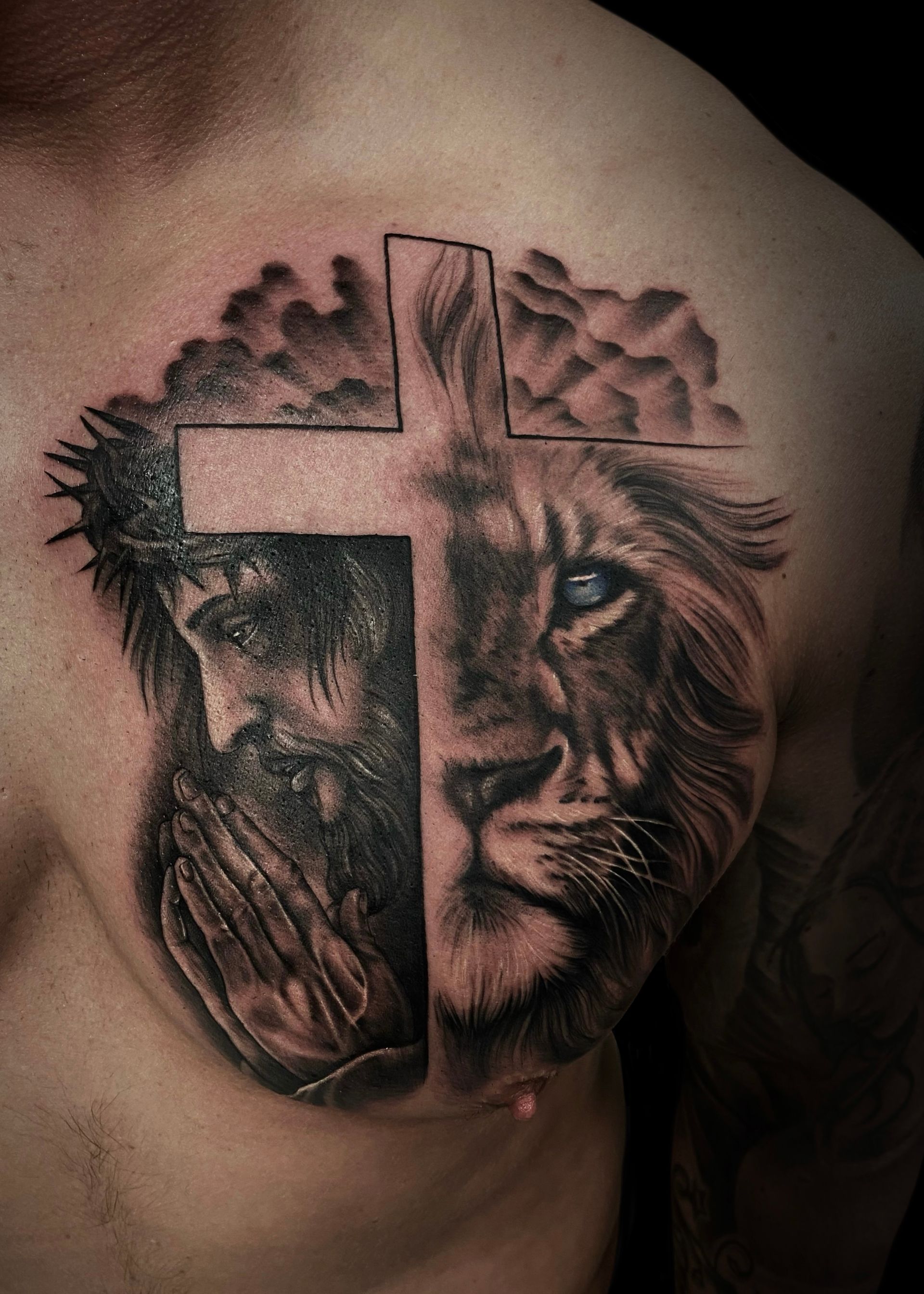 Black und White Tattoo von Jesus, einem Kreuz und einem Löwen daneben mit blauen Augen