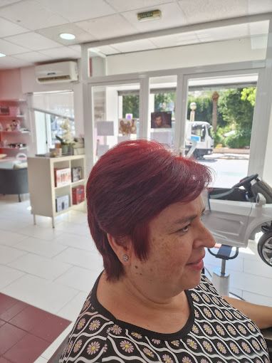 Una mujer pelirroja se está cortando el pelo en un salón.