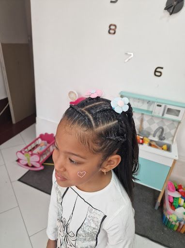 Una niña con trenzas en el pelo y una flor en el pelo.