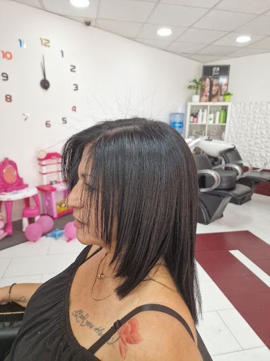 Una mujer está sentada en una silla en un salón con un reloj en la pared detrás de ella.