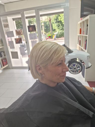 Una mujer se está cortando el pelo en un salón con un coche de juguete de fondo.