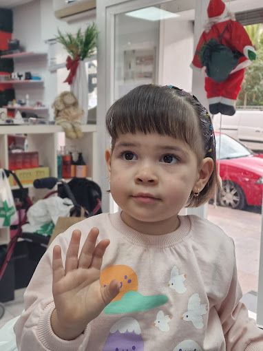 Una niña agita su mano frente a una ventana.