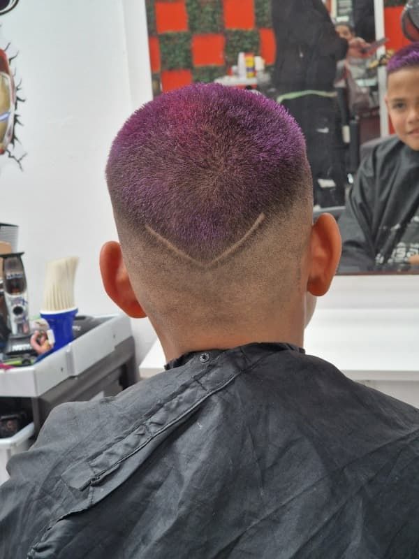 Un hombre con cabello morado se está cortando el pelo en un barbero.