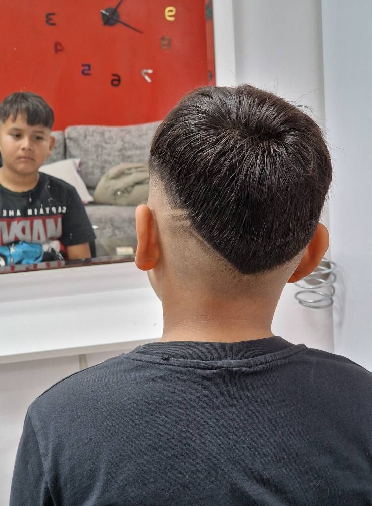 Un niño pequeño se corta el pelo frente a un espejo.