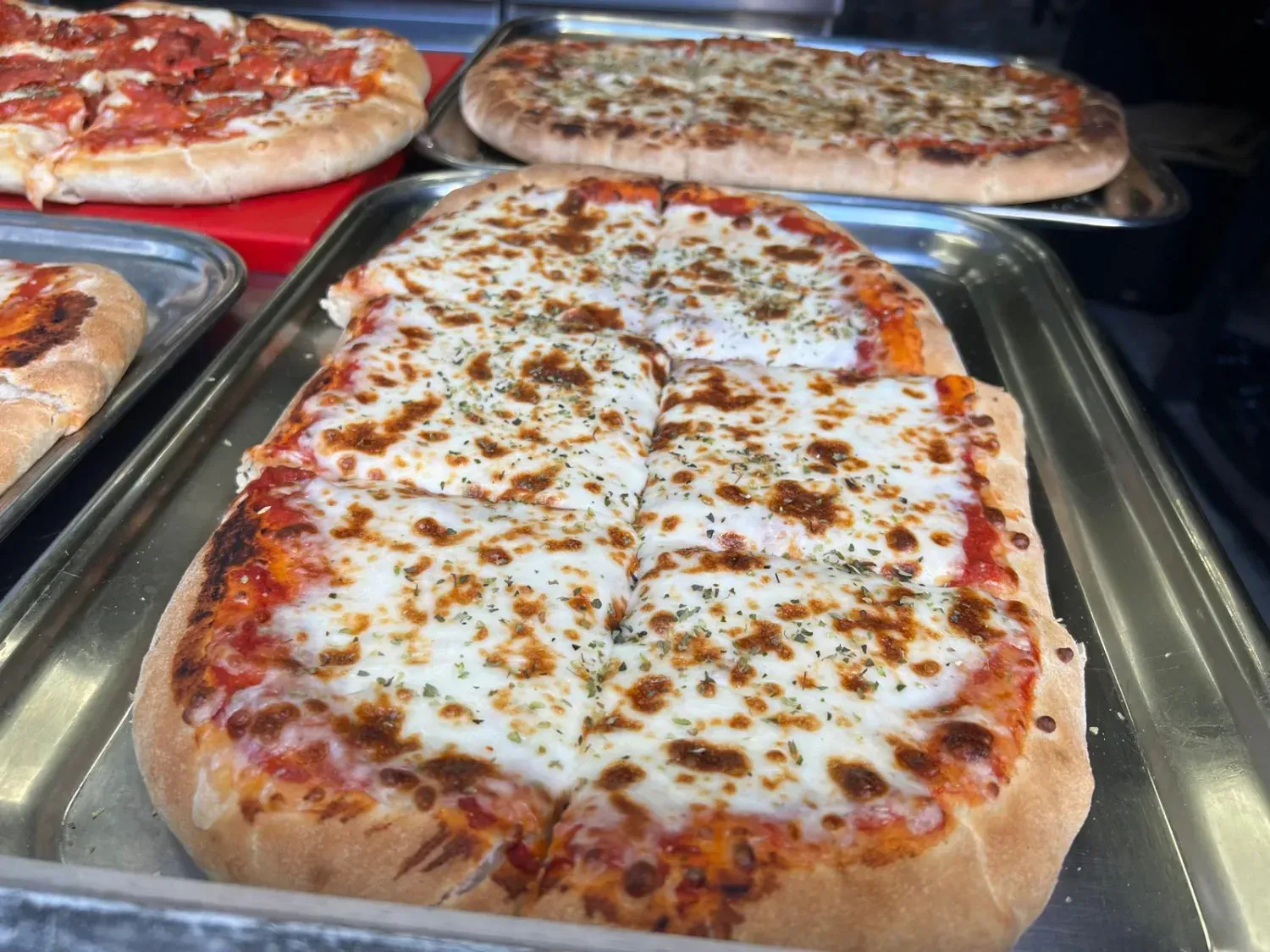 Pizza cubierta con prosciutto, berenjena y queso parmesano en un plato blanco.