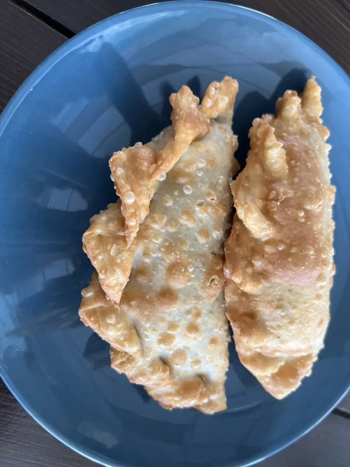 Chuletas de cordero a la parrilla en un recipiente de terracota sobre una tabla de madera.