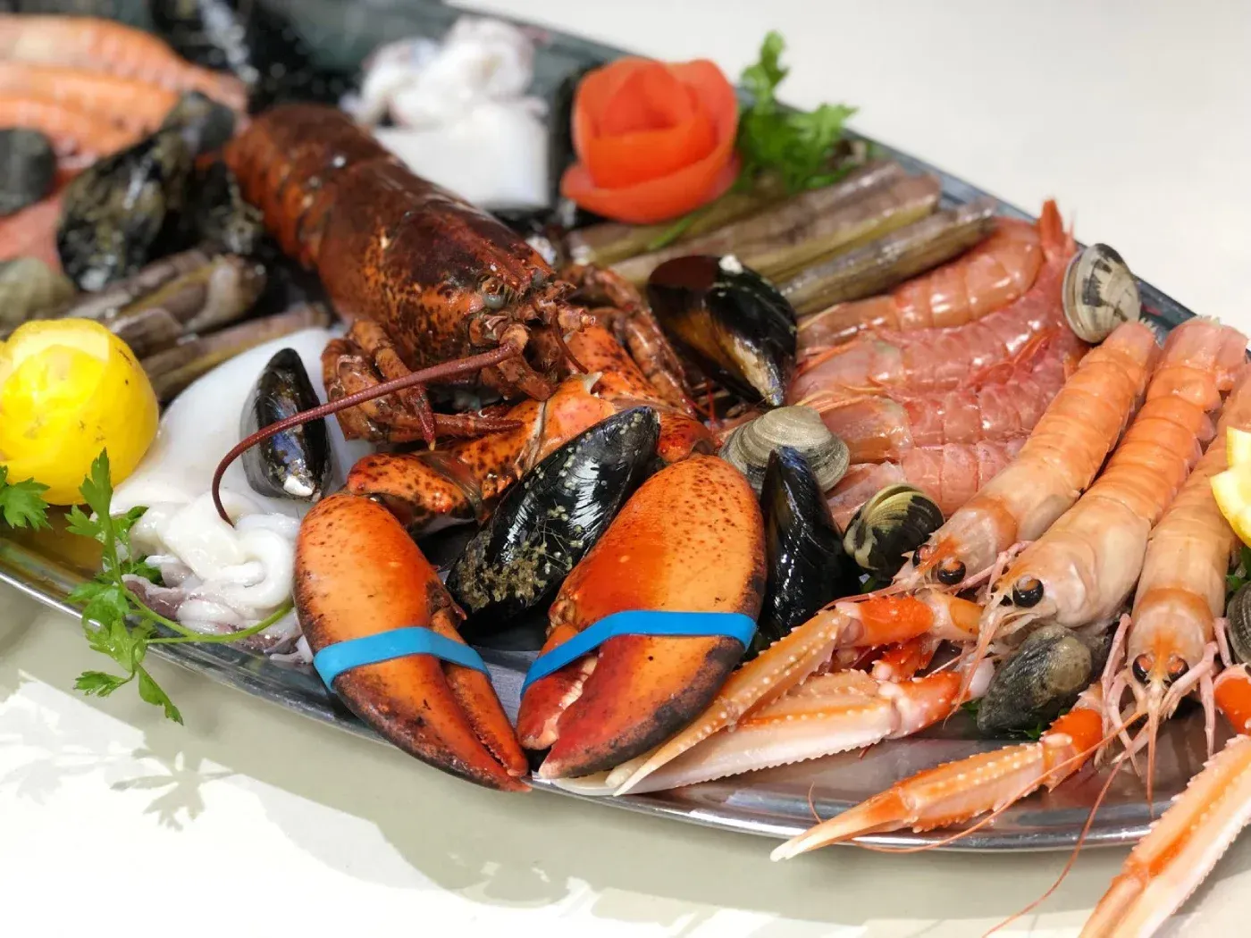 Plato de mariscos con langosta, camarones, mejillones y almejas en bandeja de plata.