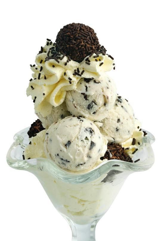 Sundae de helado en vaso, con bolas de helado de galletas y crema, crema batida y chispas de chocolate.