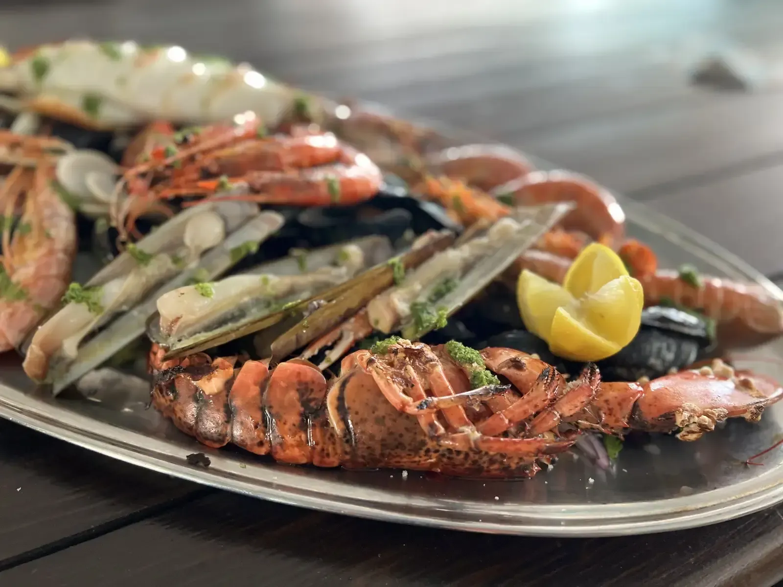 Plato de mariscos: langosta, camarones, mejillones, almejas y limón en plato de plata.